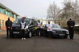 5 men stood in front of 2 black cars