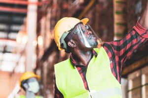 Man in hard hat and hi-vis reaching to a shelf