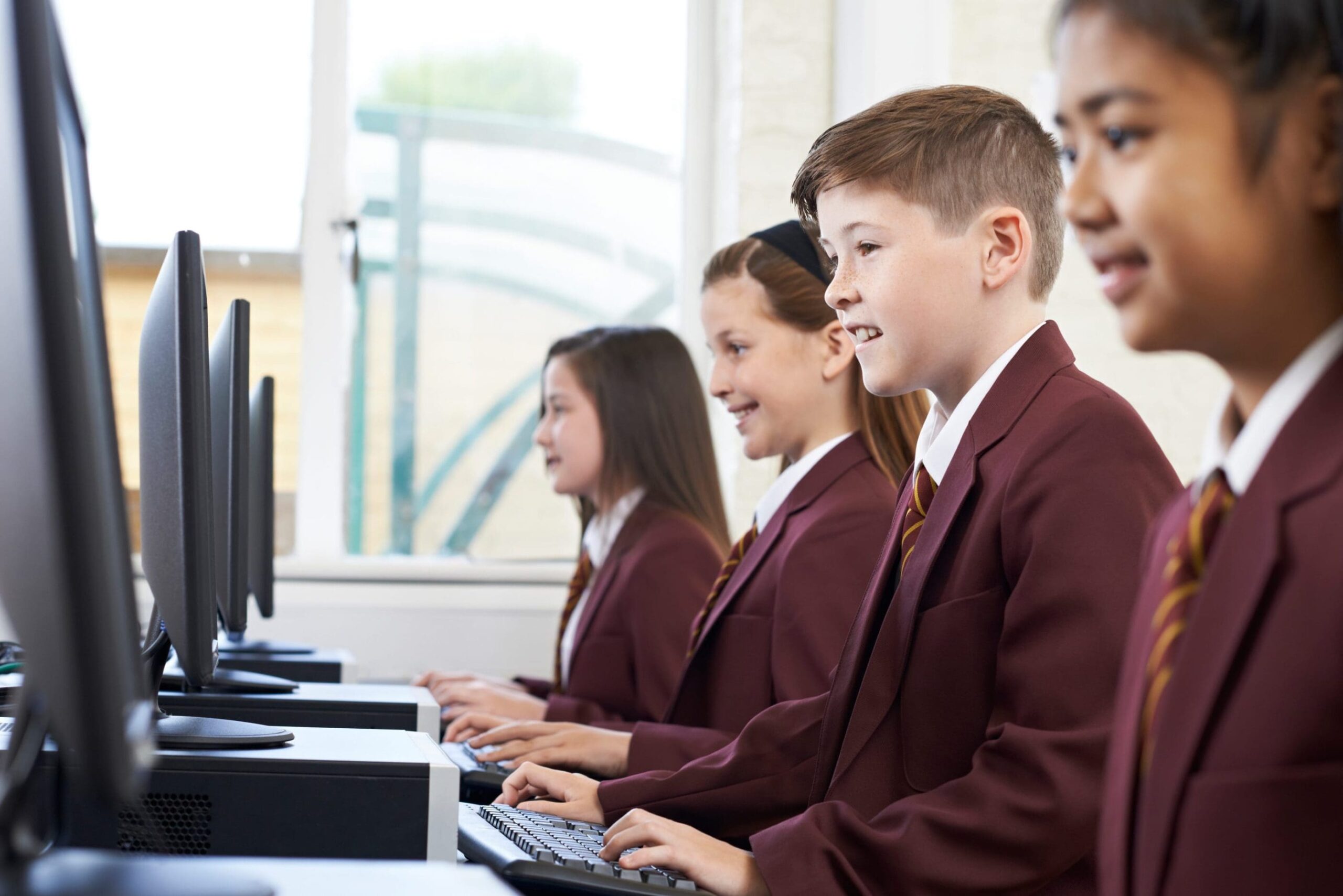 4 children in school uniform looking at computer screens